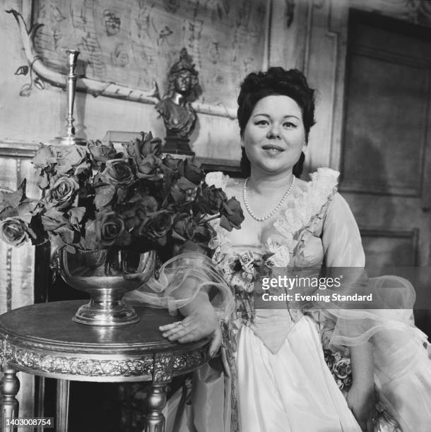 Italian soprano Renata Scotto in costume as Manon Lescaut beside a floral display of roses on a small table, part of the stage set of Jules...