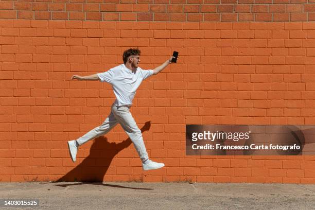 happy teen boy jumping and running - street running stock pictures, royalty-free photos & images