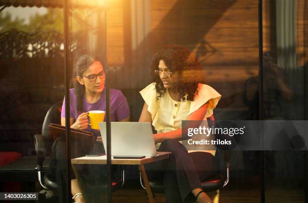 two female colleagues using laptop at cafe - two cups of coffee stock pictures, royalty-free photos & images