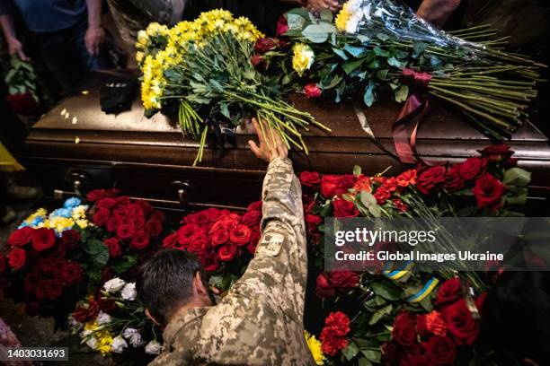 Ukrainian military member kneels near the coffin to honor the memory of Volodymyr Prymachenko, known as Kherson, Head of the Kyiv department of The...