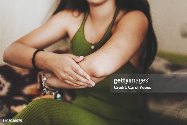 medium shot female  rubbing lotion into arms and  elbows. space for copy. - complexion fotografías e imágenes de stock