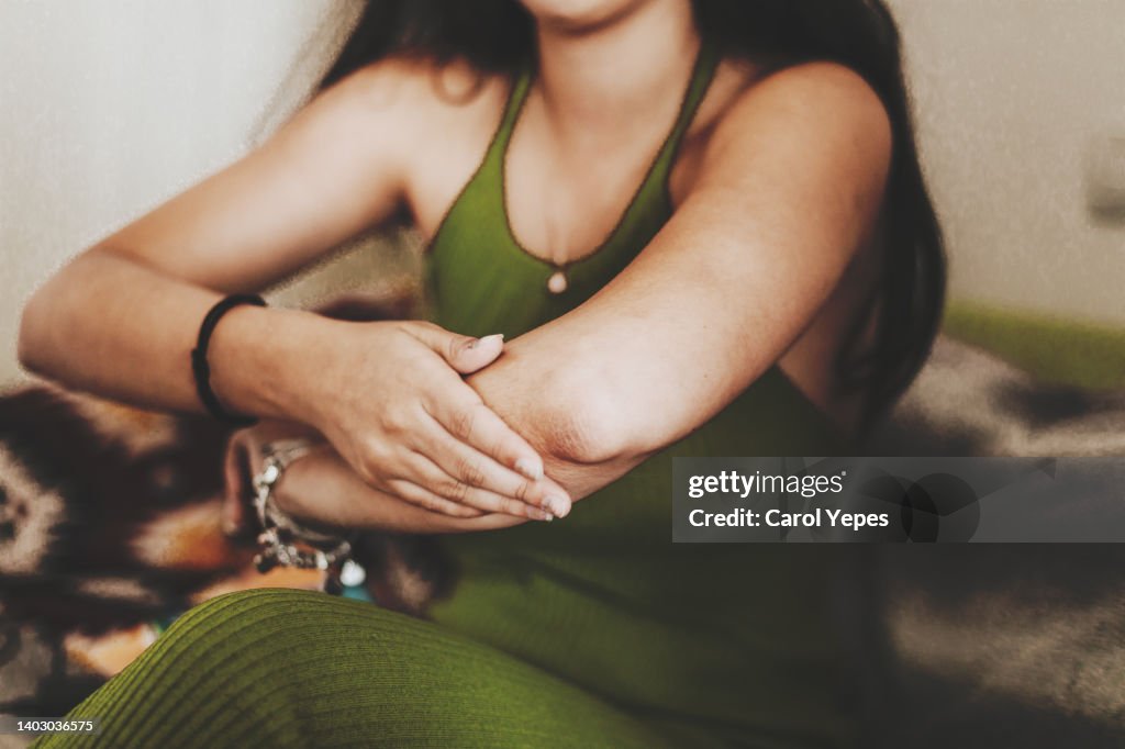Medium shot female rubbing lotion into arms and elbows. Space for copy.
