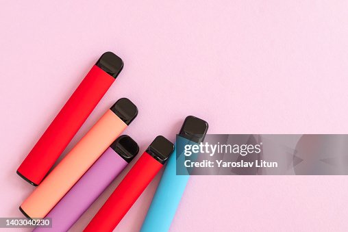Layout of colorful disposable electronic cigarettes on a purple pink background. The concept of modern smoking, vaping and nicotine. Top view Layout of colorful disposable electronic cigarettes on a purple pink background. The concept of modern smoking, vaping and nicotine. Top view