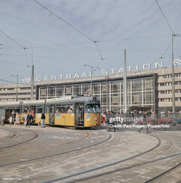 Pedestrians walk past a tram stopped on Stationsplein in front of Centraal Station in the centrum area of the city of Rotterdam in the province of...