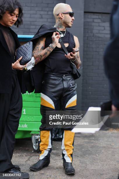 Guest is seen wearing a Pair of Black Leather with Orange Trim Bikers Trousers with a Black Leather Bag. At The University of Westminster MA Menswear...
