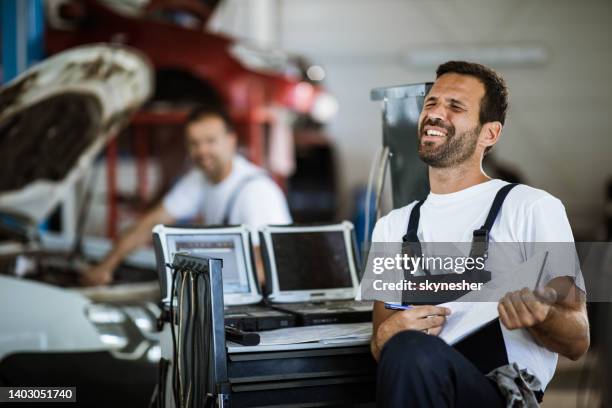 young mechanic having fun in auto repair shop. - zingende man stockfoto's en -beelden