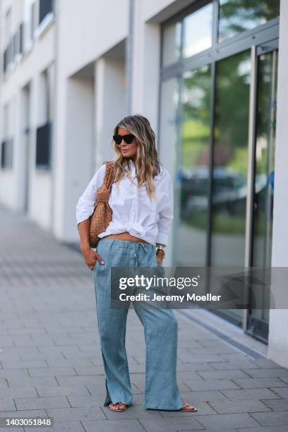 Gitta Banko seen wearing a black sunglasses from Bottega Veneta, a white shirt blouse from Acne Studios, a blue linen pants from Crossley, rhinestone...