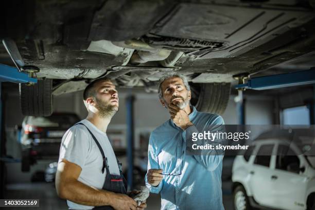mid adult customer and auto repairman analyzing chassis in a workshop. - chassis stock pictures, royalty-free photos & images