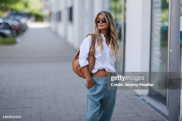 Gitta Banko seen wearing a black sunglasses from Bottega Veneta, a white shirt blouse from Acne Studios, a blue linen pants from Crossley and a brown...