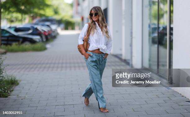 Gitta Banko seen wearing a black sunglasses from Bottega Veneta, a white shirt blouse from Acne Studios, a blue linen pants from Crossley, rhinestone...