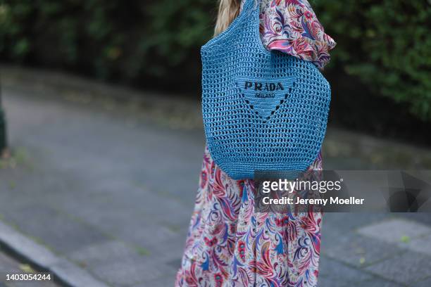 Gitta Banko seen wearing a long maxi floral dress from Dea Kudibal with long sleeves and a blue bast raffia tote bag from Prada on June 12, 2022 in...