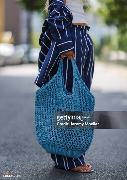 Gitta Banko seen wearing a blue/white striped cotton pyjama set from Yaitte, rhinestone sandals from Aminah Abdul Jillil and a blue bast raffia tote...