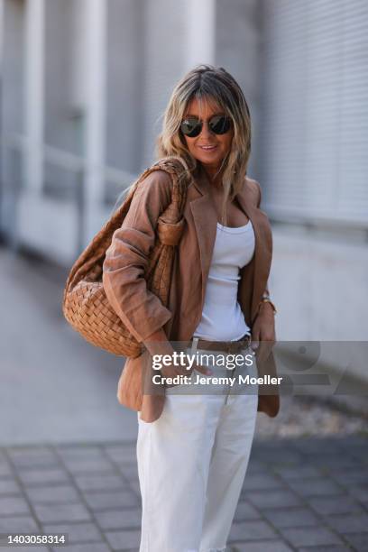 Gitta Banko seen wearing a Ray Ban sunglasses, a brown linen blazer from Darling Harbour, a white destroyed off-white denim pants from Closed, a tank...