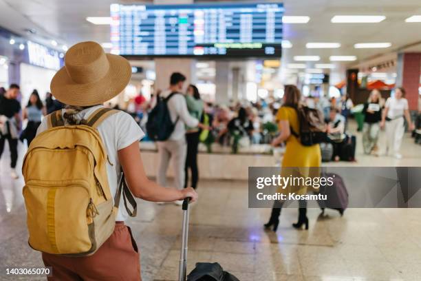 uma mulher irreconhecível com uma mochila e bagagem esperando por um avião no aeroporto - balcão de check in do aeroporto - fotografias e filmes do acervo