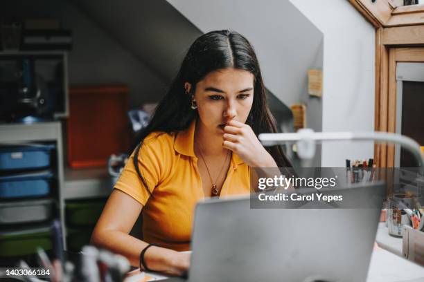 hispanic college student doing some home works from home with laptop - toples stockfoto's en -beelden