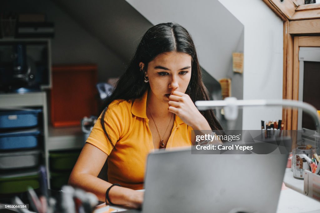 Hispanic college student doing some home works from home with laptop
