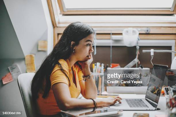 hispanic young woman working and studying from home using laptop - learning resources for reading stock-fotos und bilder