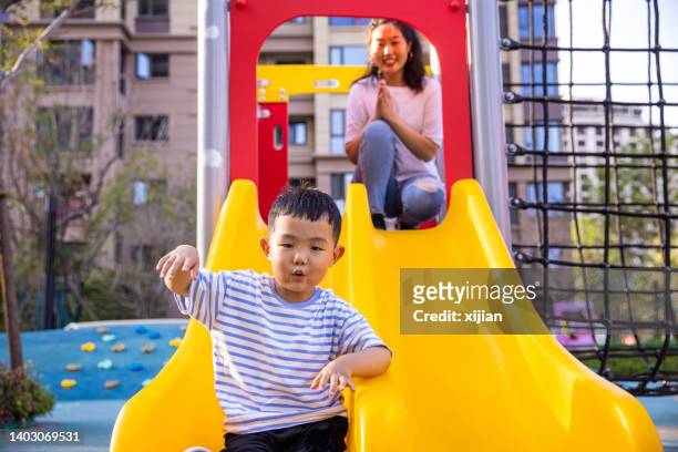 mutter und sohn spielen auf der rutsche - mother and son at playground stock-fotos und bilder