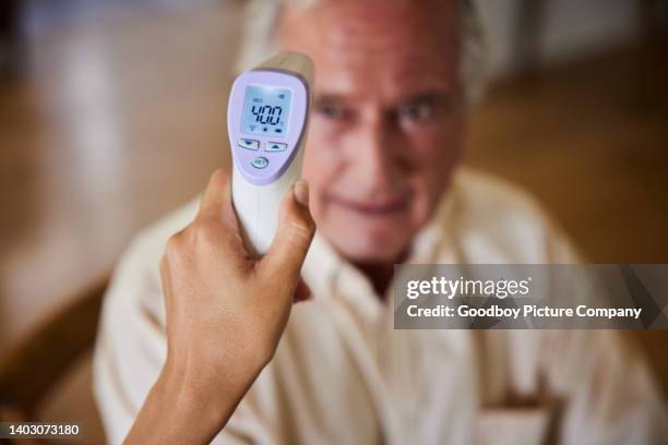 uomo anziano con la febbre che ha la temperatura misurata da un'infermiera - misurare la temperatura foto e immagini stock