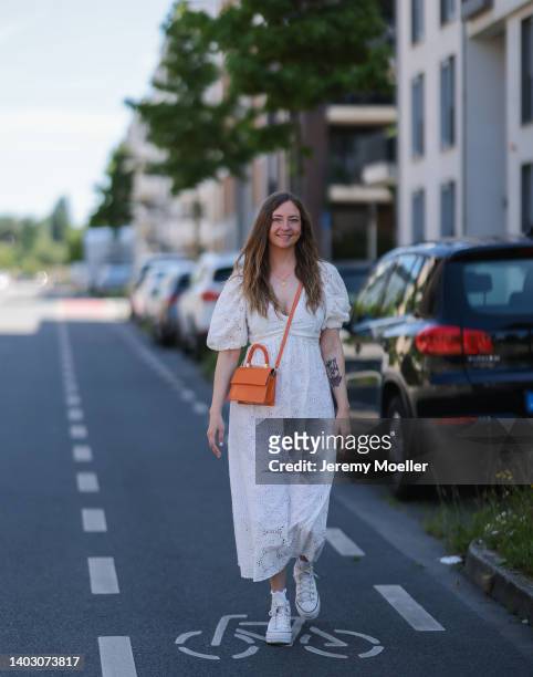 Dana Lohmüller seen wearing a white maxi dress, white socks, white chucks from Converse and an orange leather crossbody bag on June 11, 2022 in...