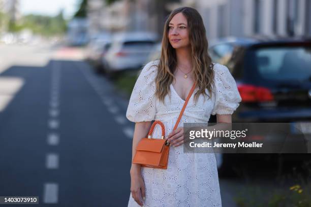 Dana Lohmüller seen wearing a white maxi dress and an orange leather crossbody bag on June 11, 2022 in Dusseldorf, Germany.