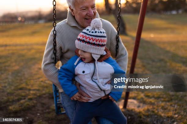 toddler boy enjoy the swing time with grandfather - children swinging stock pictures, royalty-free photos & images