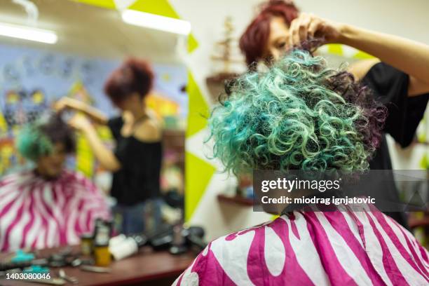 female hairdresser, cutting teenage boy half dyed blue curly hair - cool blue salon stock pictures, royalty-free photos & images