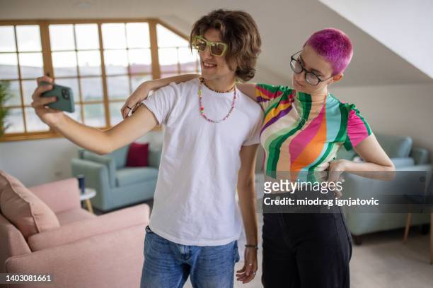 woman with pink hair taking seflie with her male friend - modern boy hipster stock pictures, royalty-free photos & images