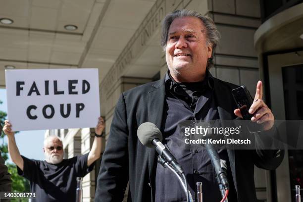 Steve Bannon, advisor to former President Donald Trump, speaks to the media as a protester stands behind him, outside of the E. Barrett Prettyman...