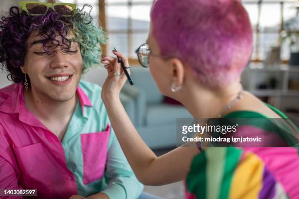 woman with pink hair doing makeup to her male friends - modern boy hipster stock pictures, royalty-free photos & images