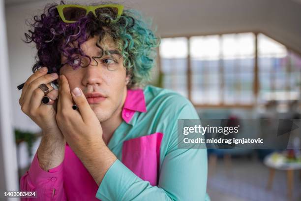 teenager mit halb gefärbten blauen haaren, der sein make-up macht - modern boy hipster stock-fotos und bilder