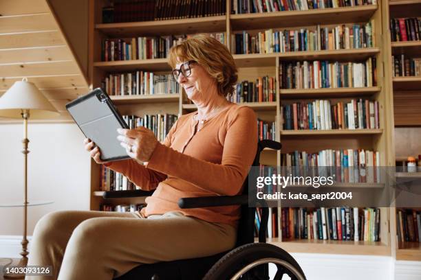 disabled senior woman using a tablet while sitting on her wheelchair - handicap 個照片及圖片檔