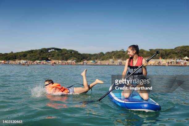 kids jumping from the sup paddleboard into the sea - tweens in bathing suits stock pictures, royalty-free photos & images