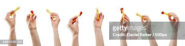 some hands with french fries in a row with mayonnaise and ketchup on white background - french fries white background stock-fotos und bilder
