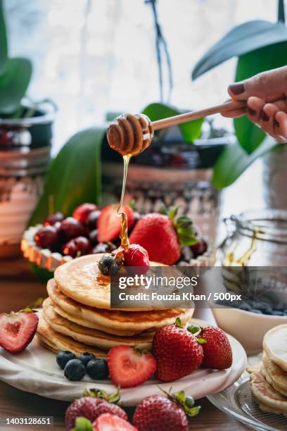 cropped hand of woman pouring honey with dipper over pancakes on table,united states,usa - american pancakes stock pictures, royalty-free photos & images