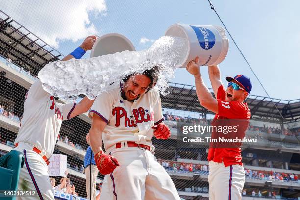 Garrett Stubbs of the Philadelphia Phillies receives a water shower from Kyle Schwarber and Rhys Hoskins after defeating the Miami Marlins at...