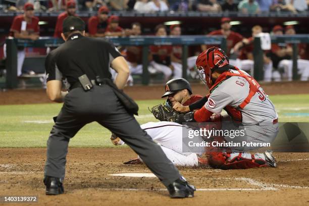 Jose Herrera of the Arizona Diamondbacks is tagged out at home plate by catcher Aramis Garcia of the Cincinnati Reds during the fifth inning of the...