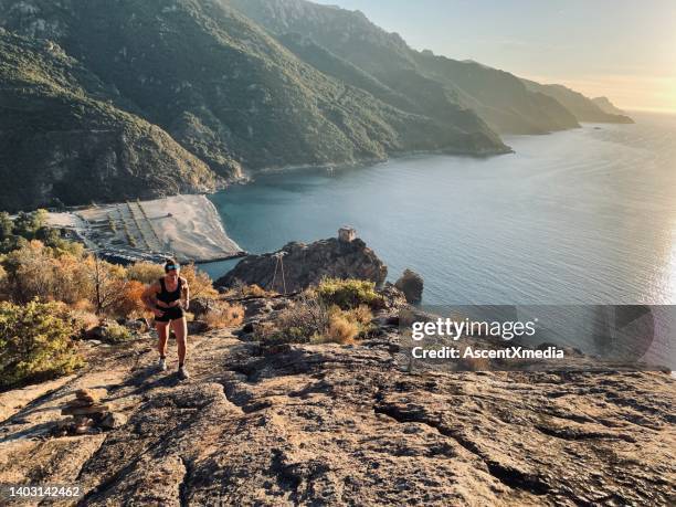 young woman runs up mountain side above sea, morning - corsica stock pictures, royalty-free photos & images