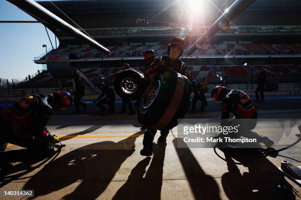 Team mechanics run out as Sebastian Vettel of Germany and Red Bull Racing drives in for a pitstop during day two of Formula One winter testing at the...