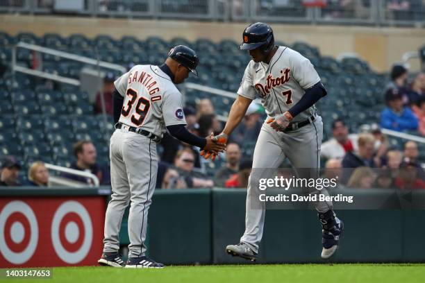 Jonathan Schoop of the Detroit Tigers celebrates his solo home run with Ramon Santiago as he rounds the bases against the Minnesota Twins in the...