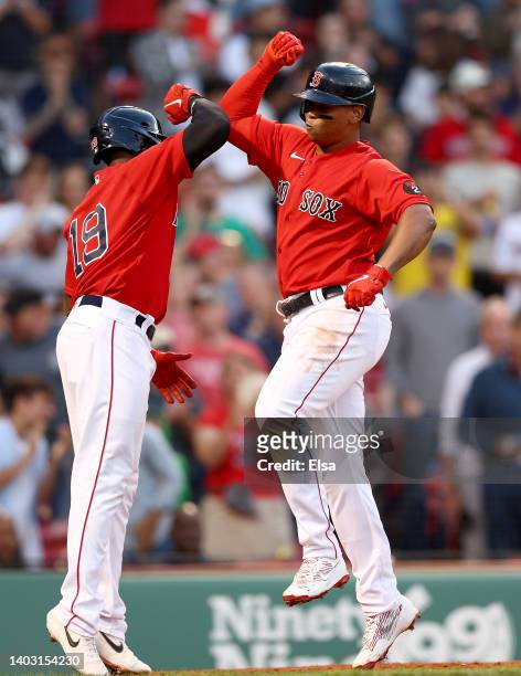 Jackie Bradley Jr. #19 of the Boston Red Sox congratulates teammate Rafael Devers after Devers drove them both home with a home run in the second...