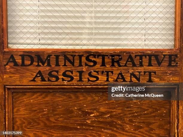 school office: old-fashioned wooden door with label “administrative assistant” & closed blinds - administrative professionals day stockfoto's en -beelden