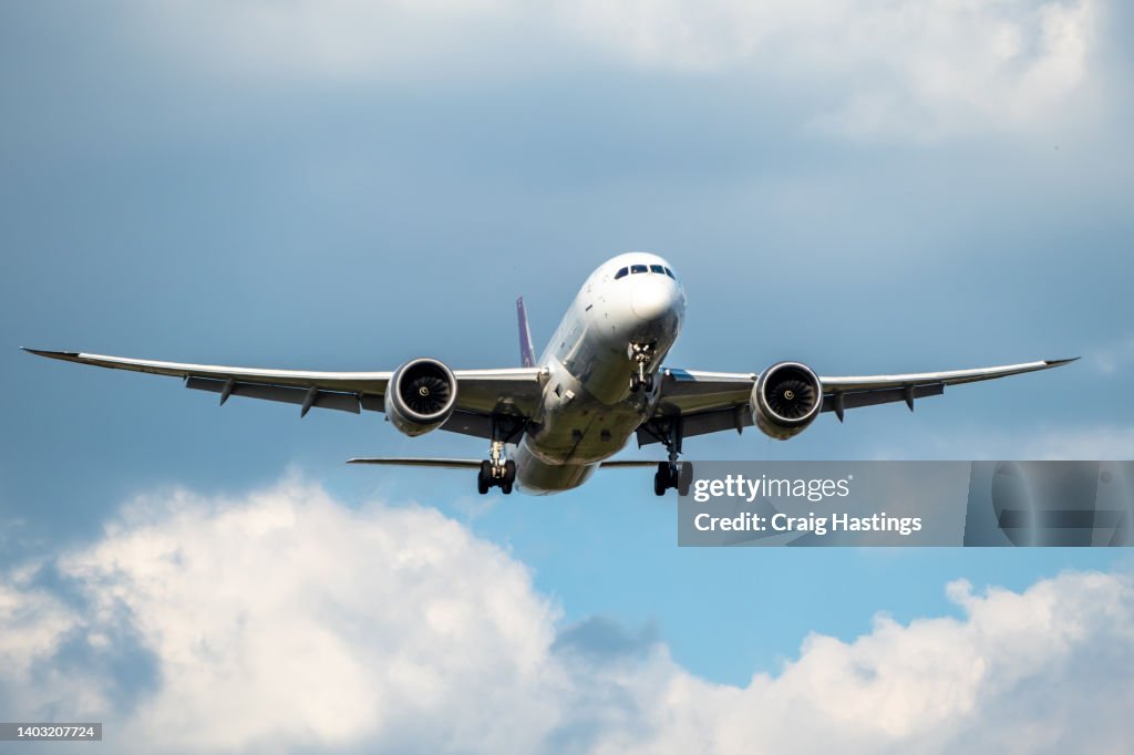 Front view of white 777 commercial flight airplane taking off or landing from the Airport runway with no visible markings or livery. Blue sky sunny back drop with some clouds