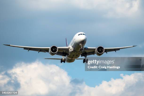 front view of white 777 commercial flight airplane taking off or landing from the airport runway with no visible markings or livery. blue sky sunny back drop with some clouds - vliegtuig stockfoto's en -beelden