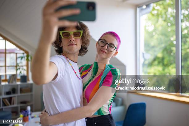 woman with pink hair taking seflie with her male friend - modern boy hipster stock pictures, royalty-free photos & images