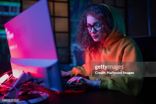 young hacker woman working on computer at dark place. - computer programmer ストックフォトと画像