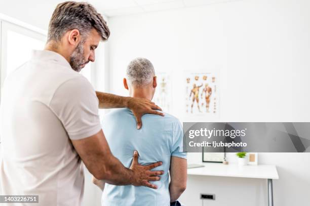 mature man having chiropractic back adjustment. - chiropractic stock pictures, royalty-free photos & images