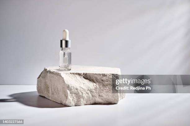 cosmetic vial with transparent cosmetic gel serum texture stands on rock podium with hard shadow. beauty concept of cosmetic products for moisturising and whitening the skin. - stein stock-fotos und bilder