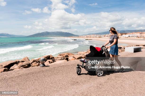 woman with baby stroller walking around the town of tarifa in cadiz, spain. - tarifa moors stock pictures, royalty-free photos & images