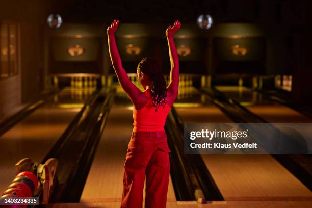 woman with hands raised standing at bowling alley - red fun stock pictures, royalty-free photos & images